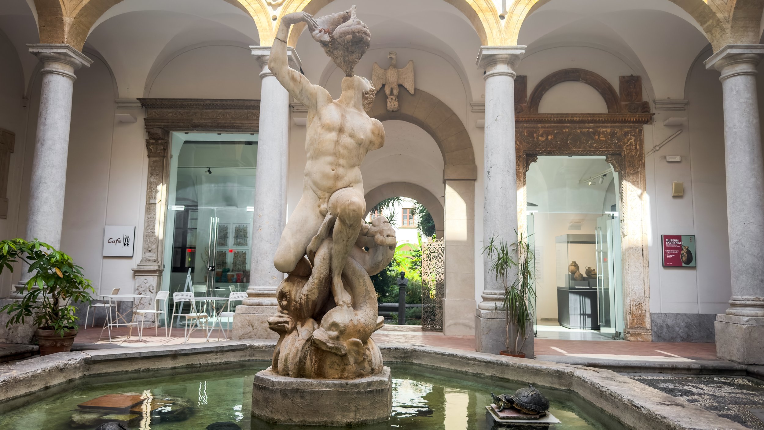 Glauco fountain with a marble statue and turtles in the arcaded courtyard of Museo Archeologico Regionale Antonino Salinas in Palermo.