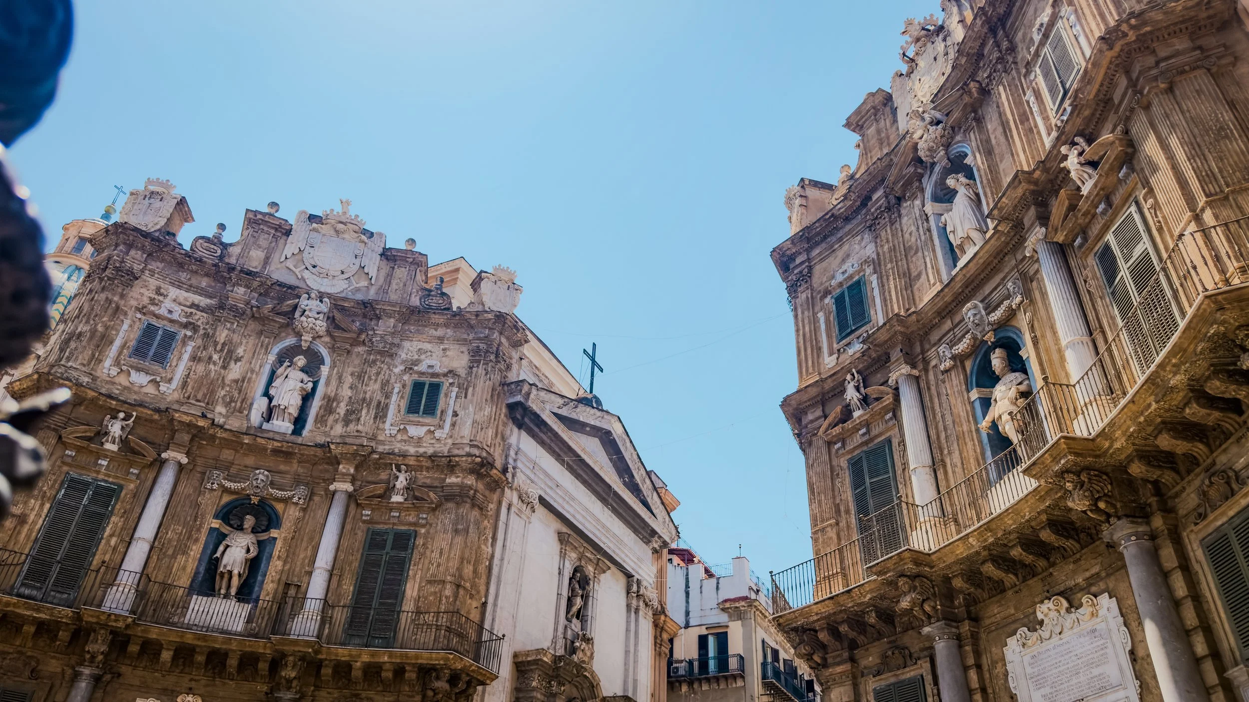 Curved Baroque façades with statues, balconies and green shutters at Quattro Canti in Palermo.
