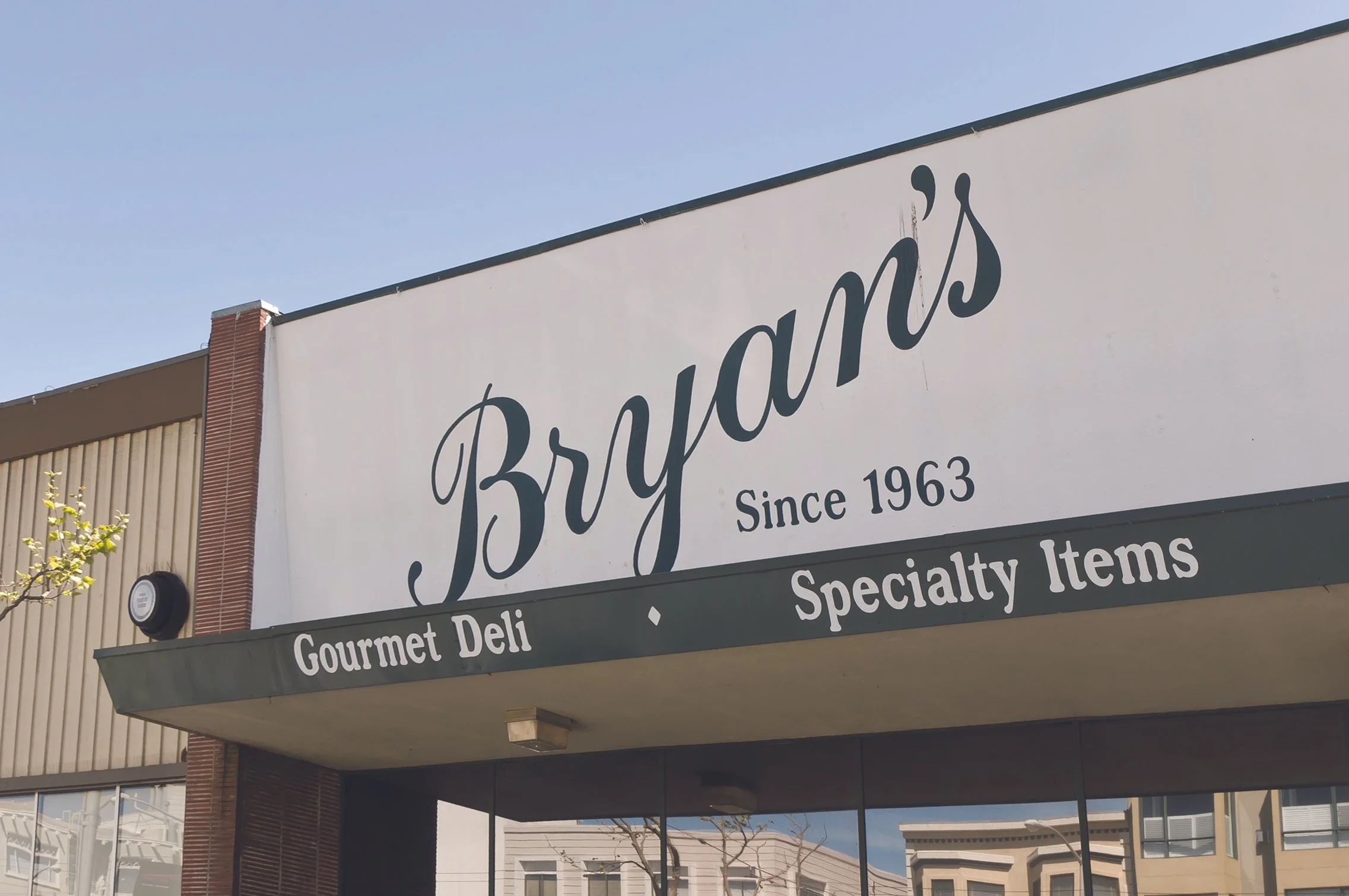 Sign on a building for a gourmet deli called Bryant's, established in 1963, offering specialty items.