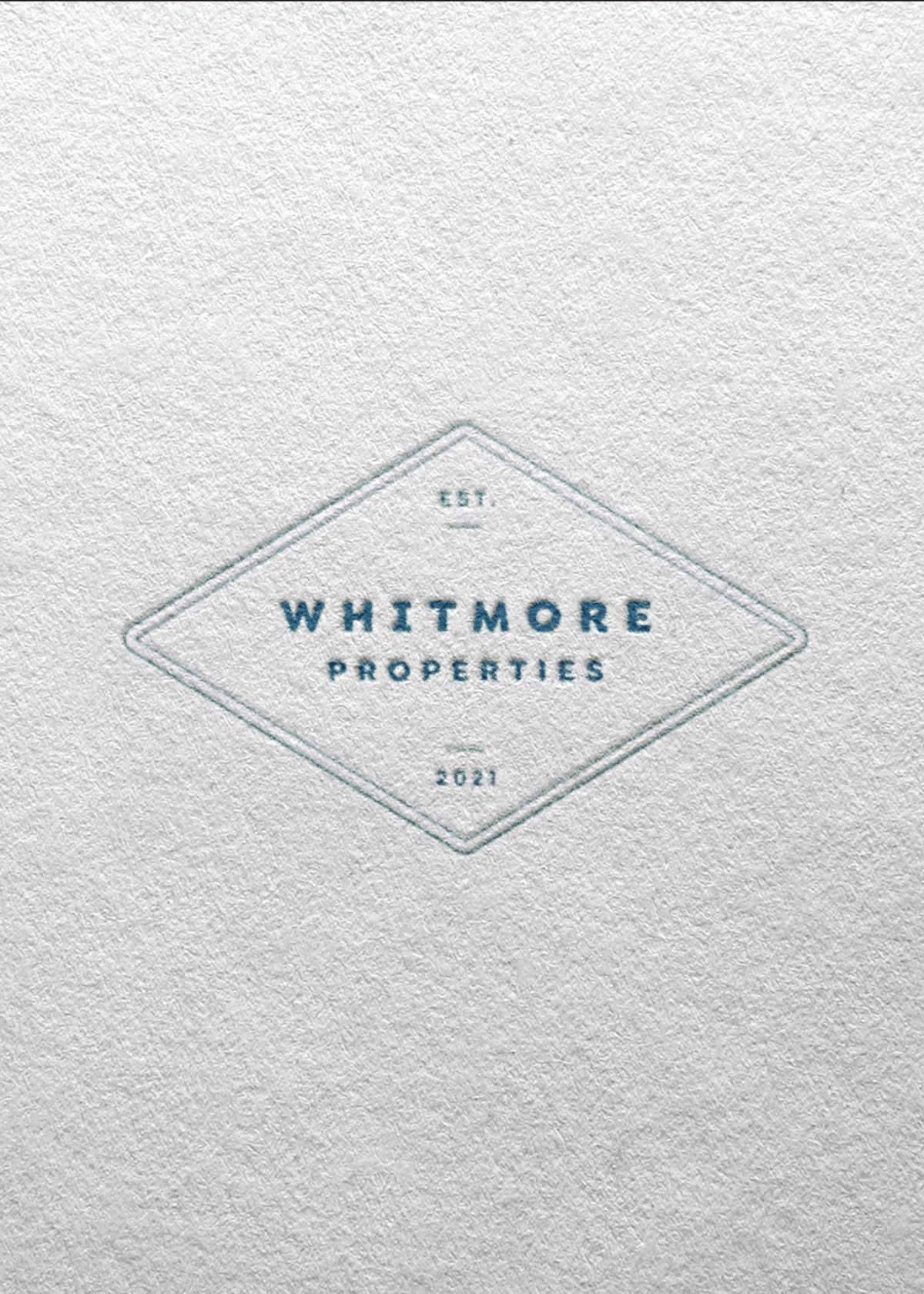 A textured white surface with a diamond-shaped logo in the center. The logo has the text 'Whitmore Properties' and 'Est. 2021' printed inside it.