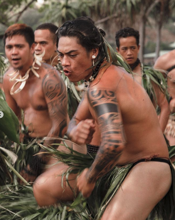 Groupe d'hommes indigènes en tenue traditionnelle, chantant et dansant lors d'une cérémonie dans la forêt tropicale.