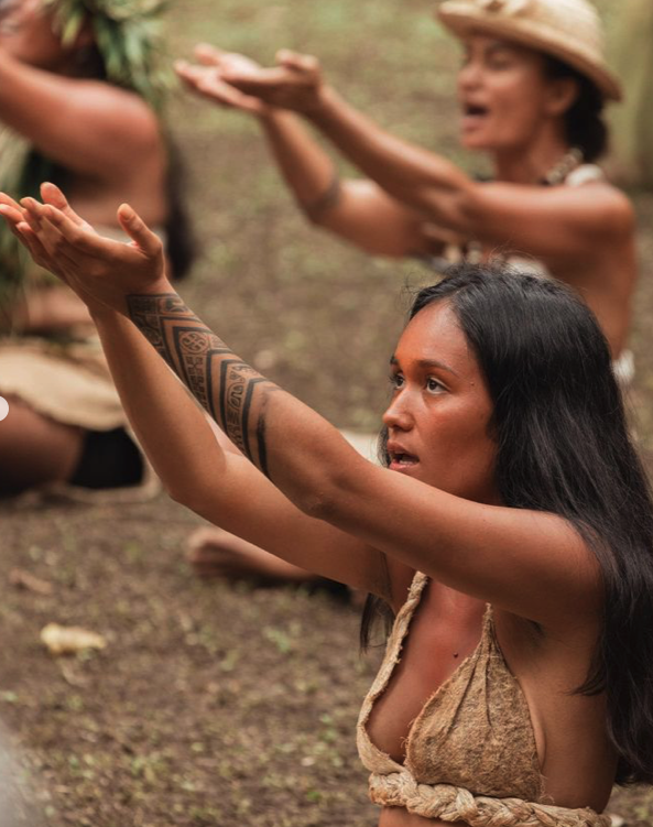 Femmes autochtones pratiquant une cérémonie ou une danse traditionnelle en plein air.