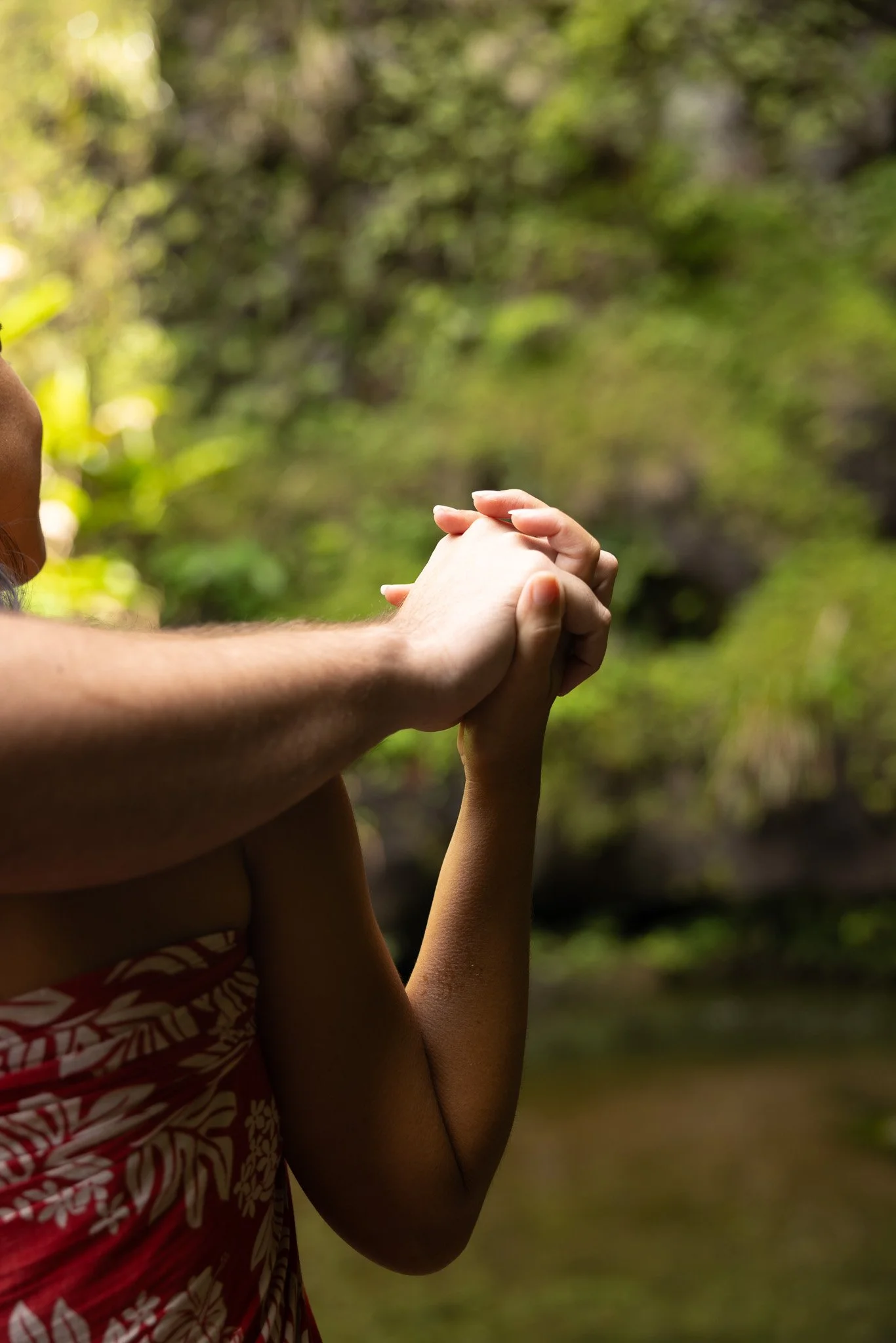 Deux mains, d'une adulte et d'un enfant, se tenant dans un environnement naturel avec des arbres en arrière-plan.