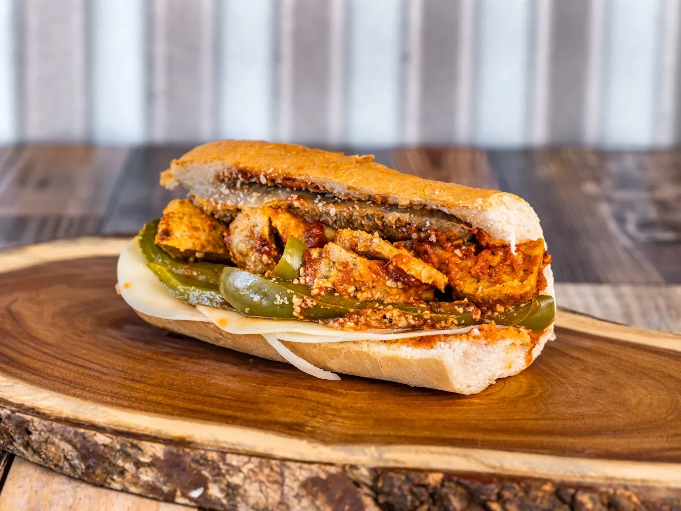 Philly cheesesteak sandwich with sliced steak, green peppers, onions, and melted cheese on a hoagie roll.