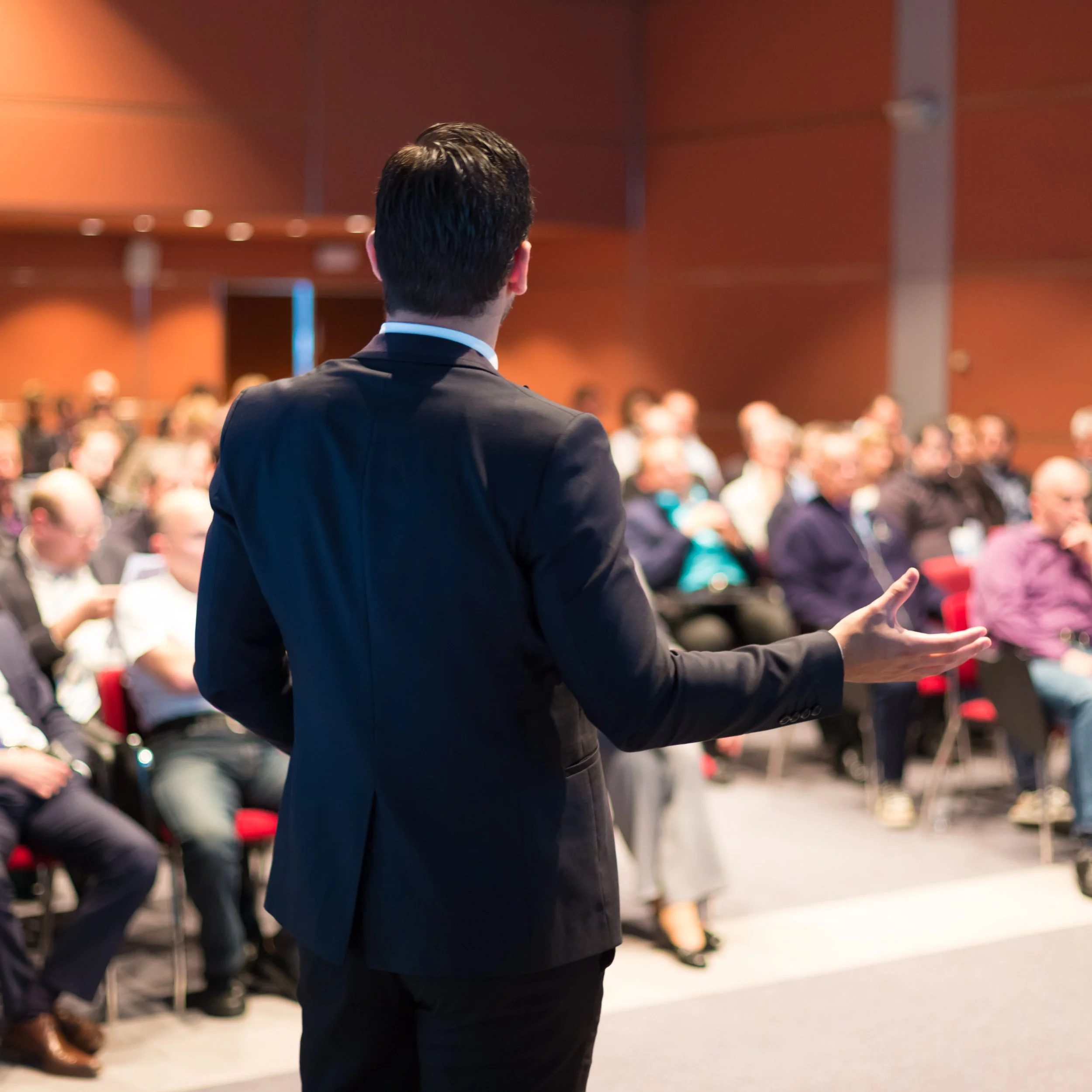 Conferencista hablando frente a distribuidores de una empresa de productos al consumidor