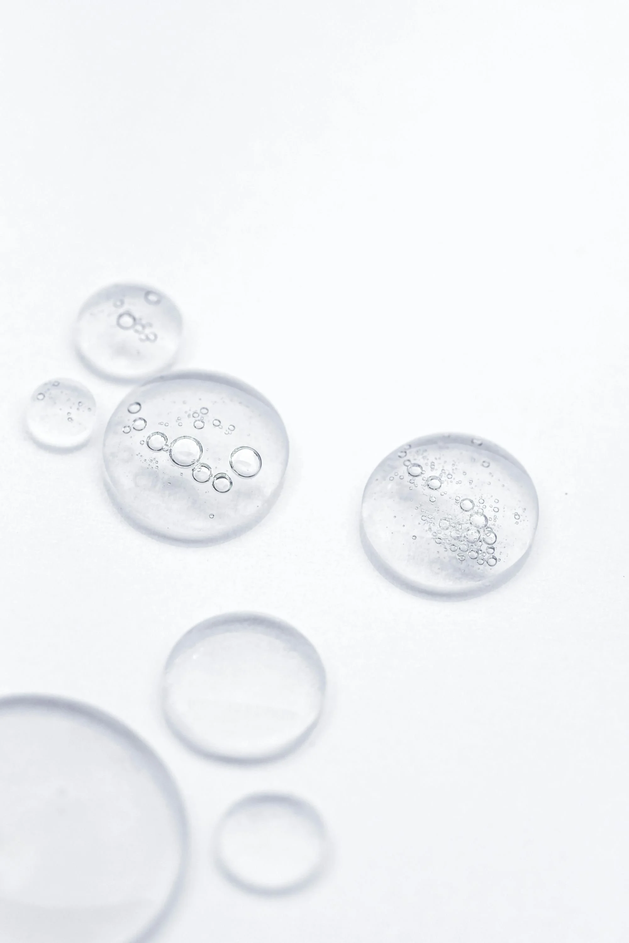 Close-up of several transparent bubbles with small bubbles inside, on a light gray background.