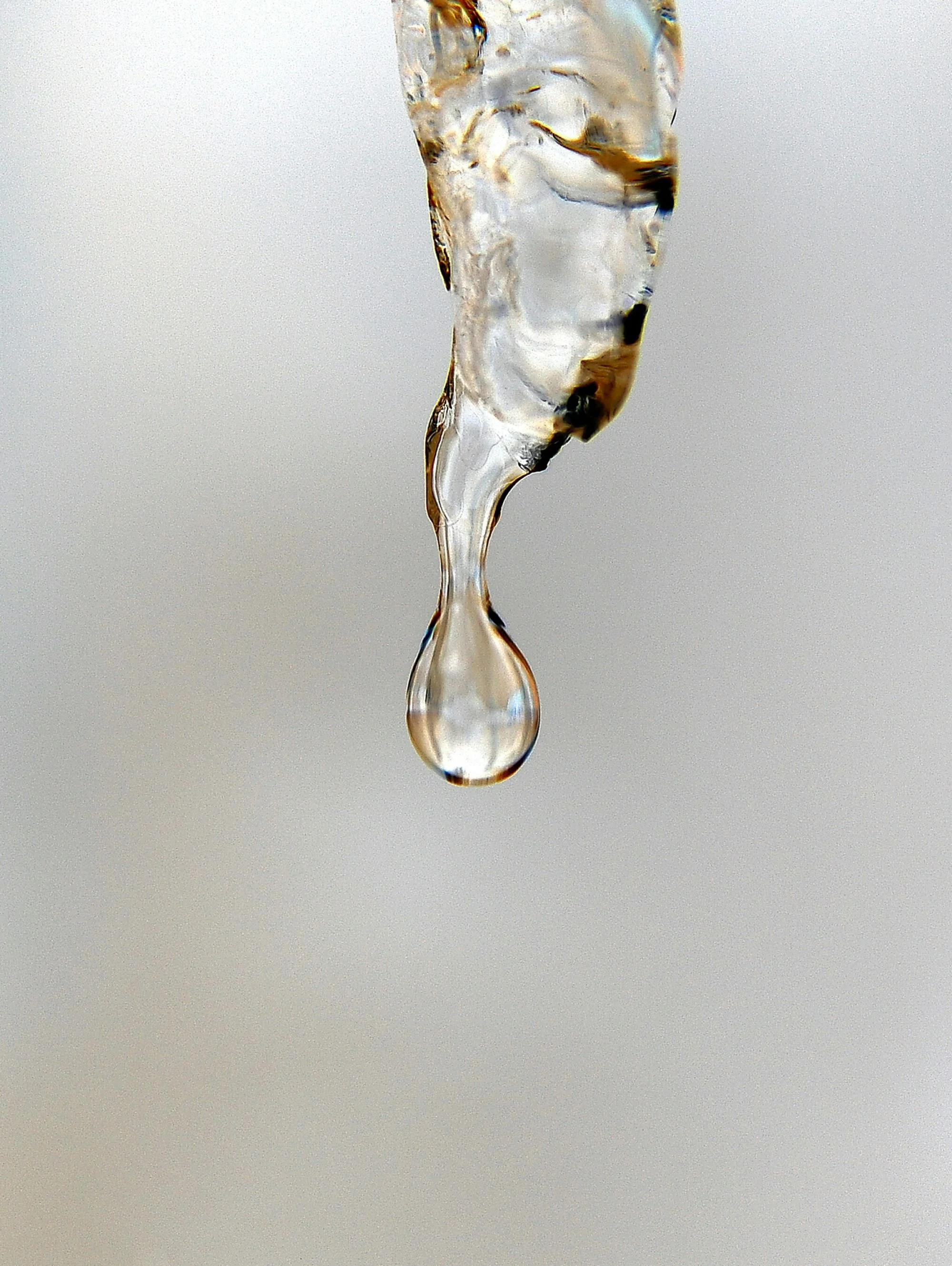 Close-up image of a water droplet falling from a splash or tap with a neutral background.