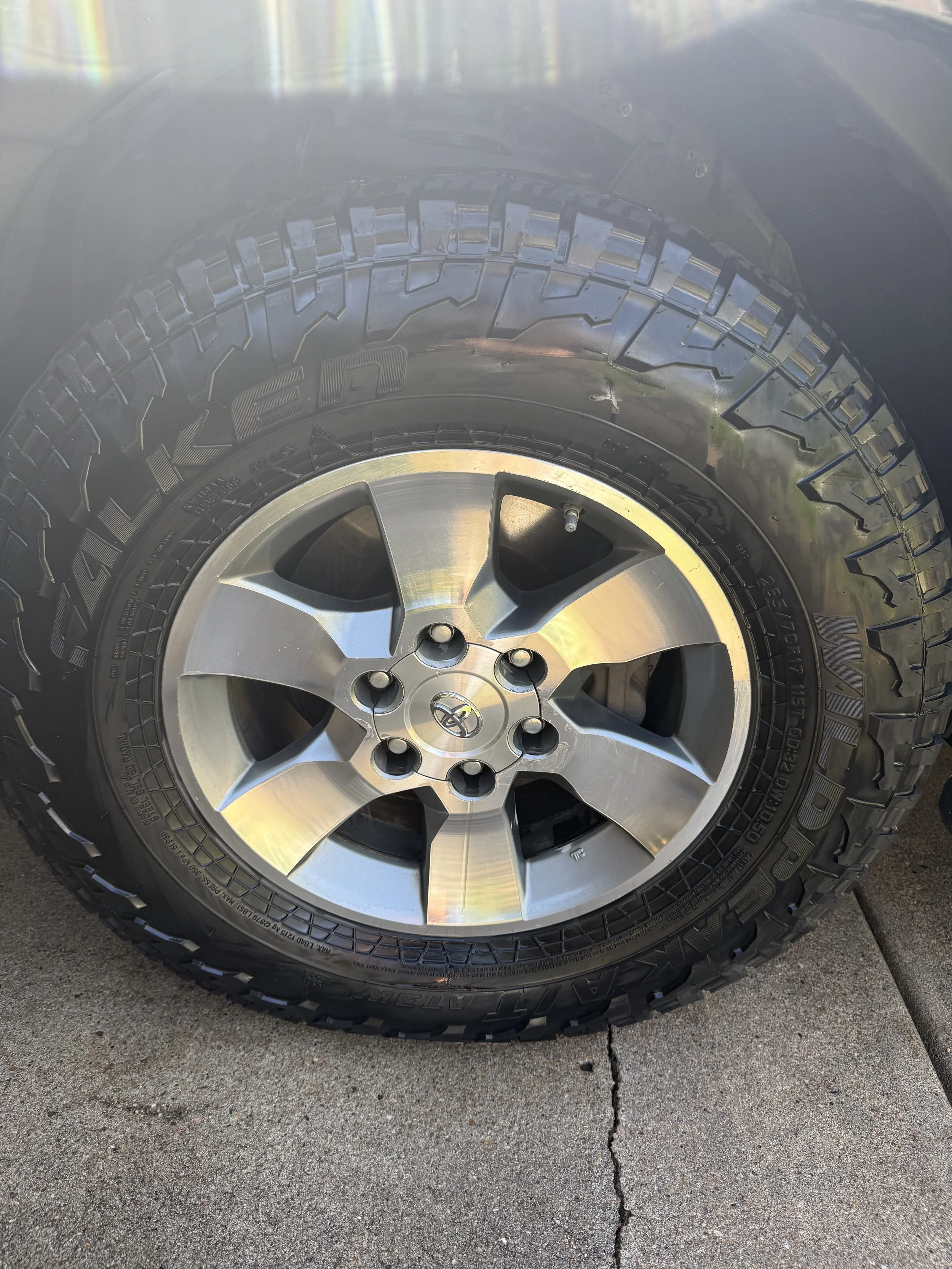 Close-up of a vehicle's tire and alloy wheel on concrete pavement with a visible crack.