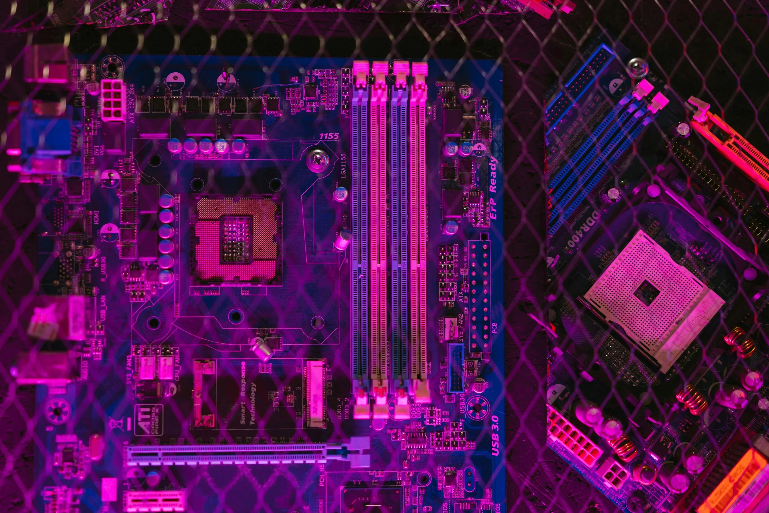 Close-up of a computer motherboard illuminated in pink and purple lighting.