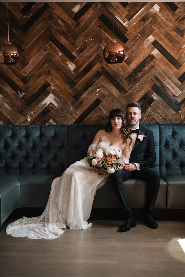 image of a couple sitting on a vintage couch in wedding attire at the joinery