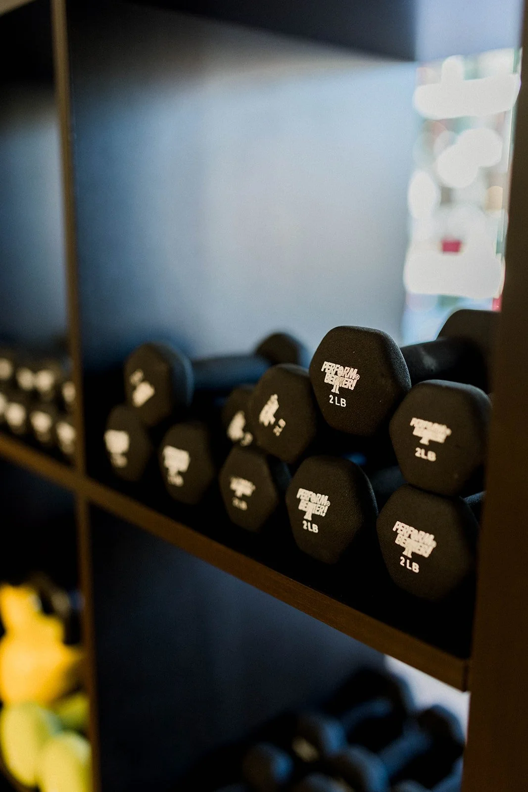 A shelf of black 2-pound dumbbells in a gym or fitness room.