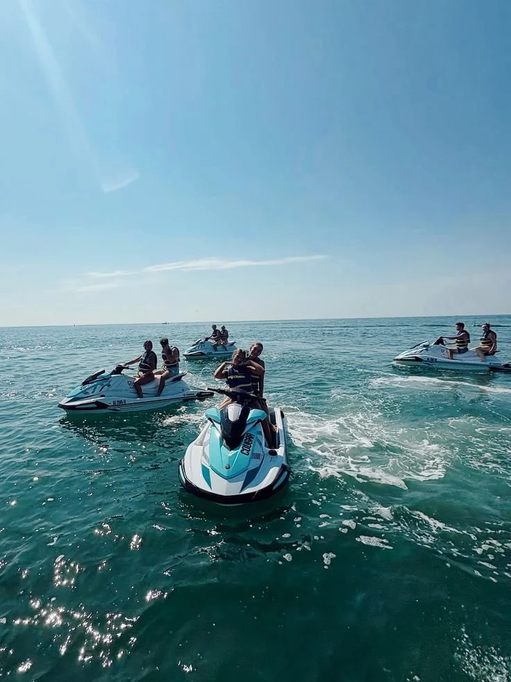 Group of people riding jet skis on the ocean under a clear blue sky.