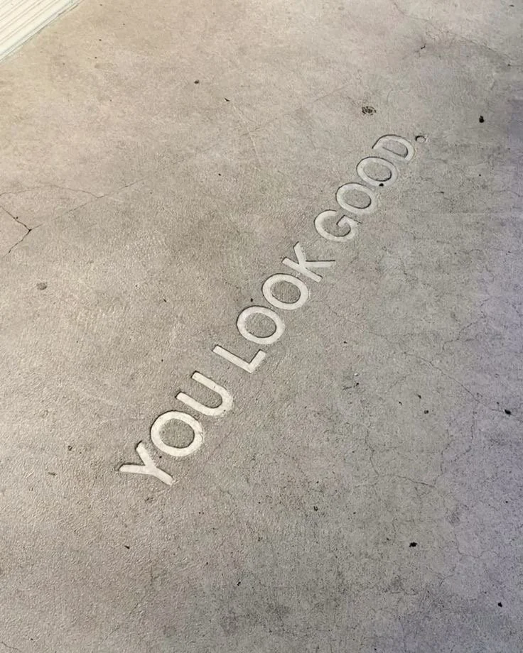 A concrete floor with the words "YOU LOOK GOOD" engraved in the surface.
