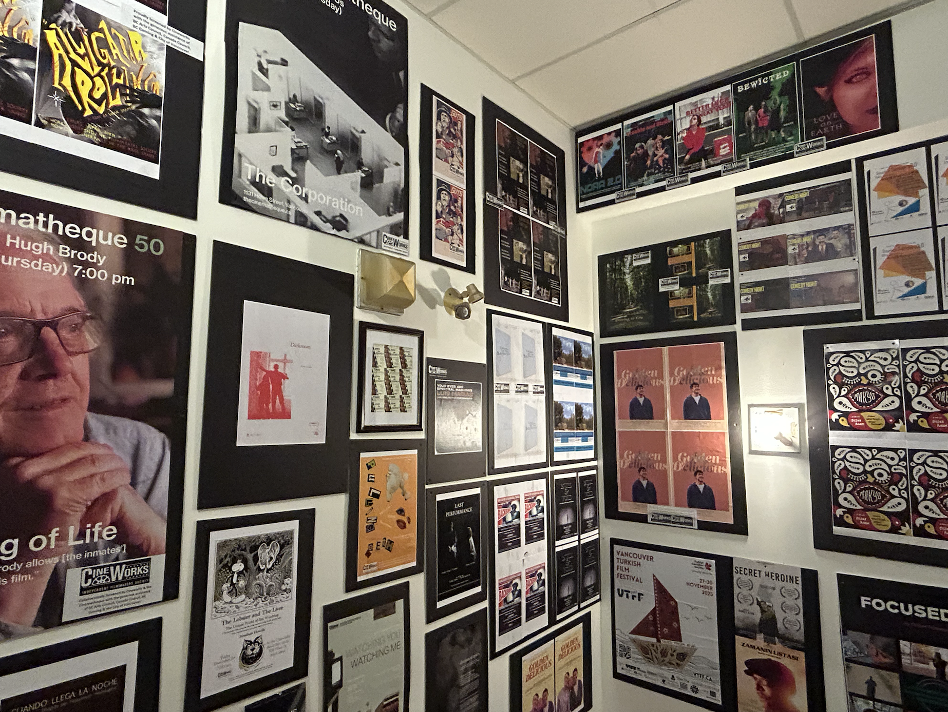 A wall filled with various framed posters and pictures, including movie posters, event posters, and artwork.