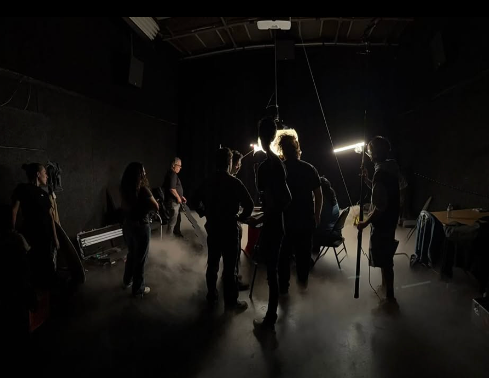 People in a dark theater or studio with bright lights creating silhouettes,  preparing for filming.