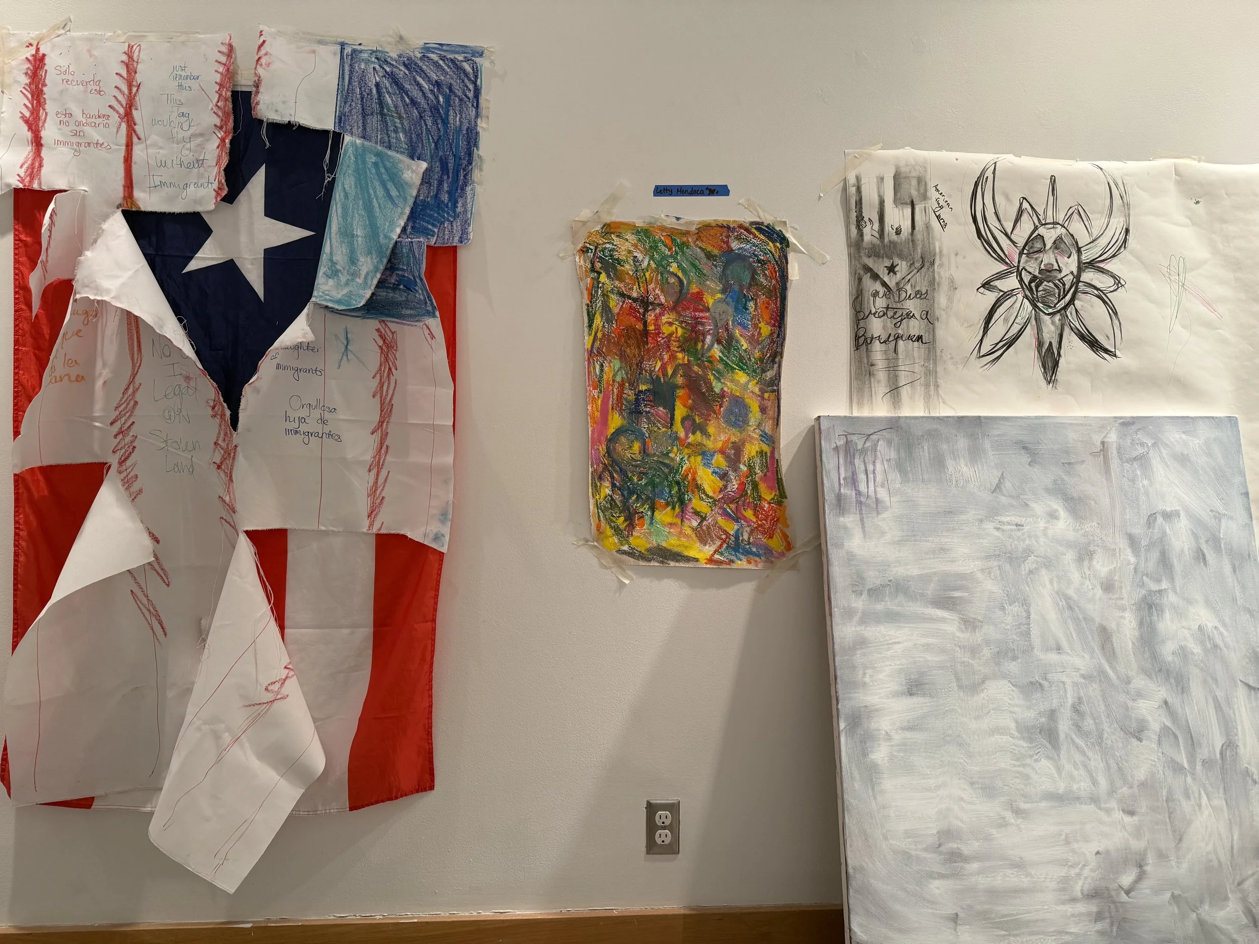 Wall display with patriotic-themed artwork and drawings, including a torn Texas flag made from paper, colorful abstract painting, and a pencil sketch of a bee or insect with an American flag and handwritten notes.