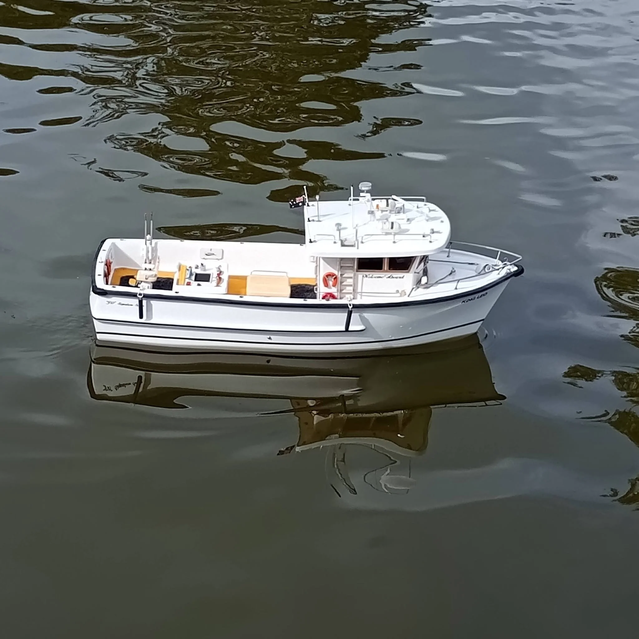 Model ship floating on water with a dark reflection.
