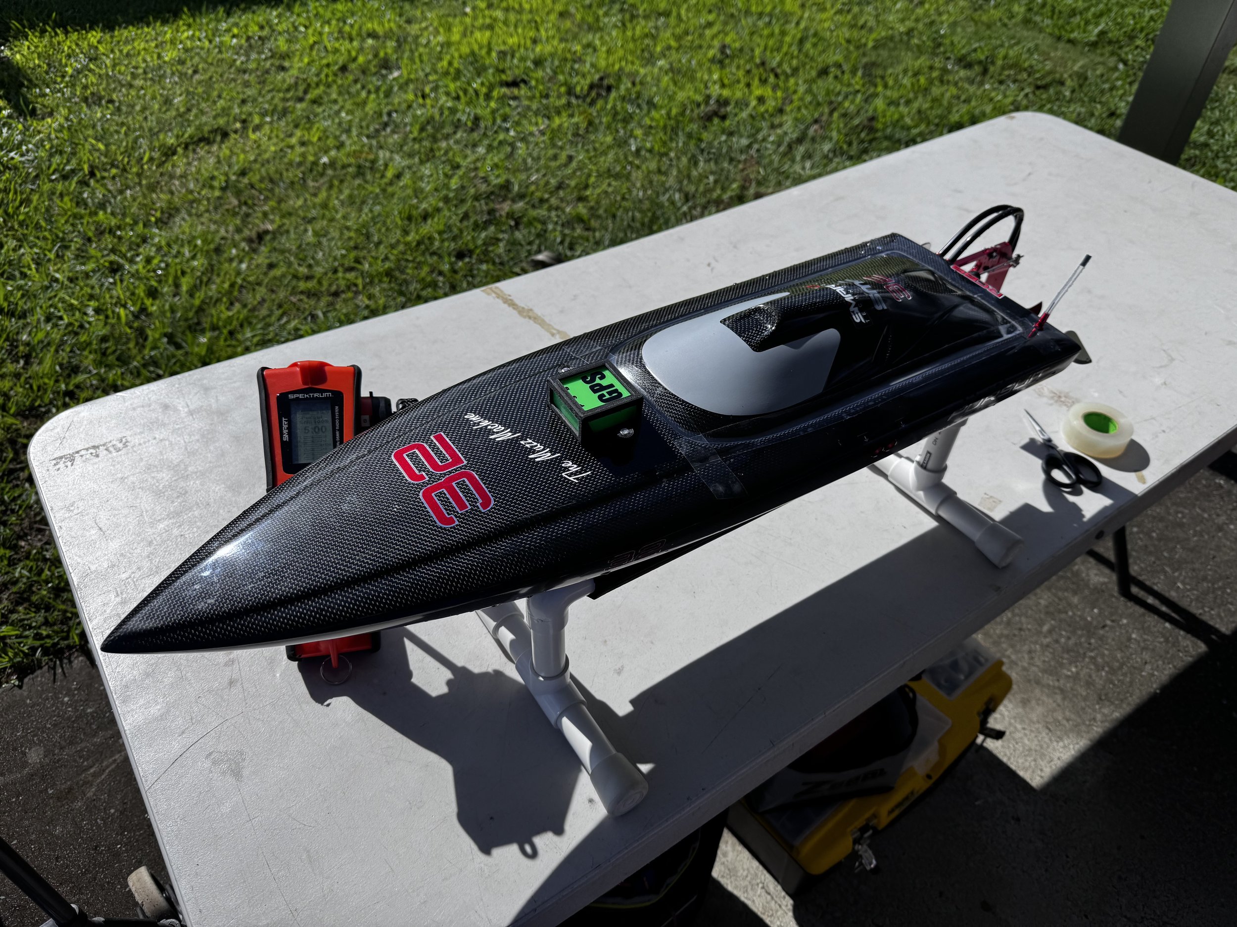Model race car on a white table outdoors, with tools and equipment nearby.