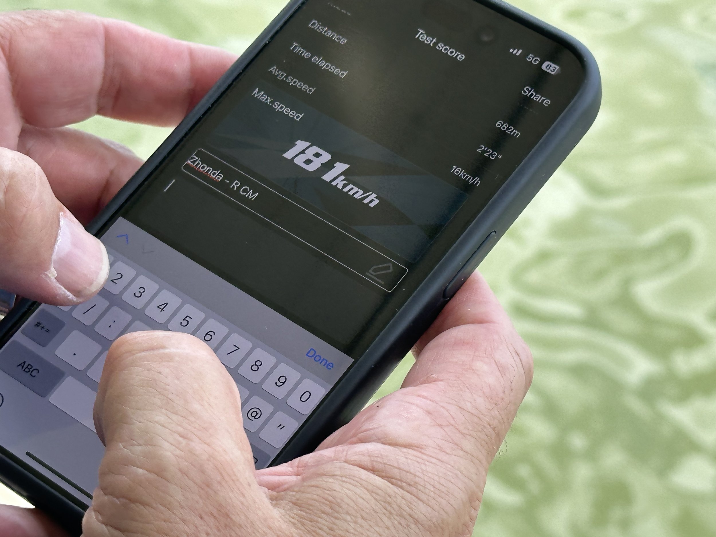 Close-up of a person's hand holding a smartphone displaying a running speed of 18.1 km/h on a fitness app or device.