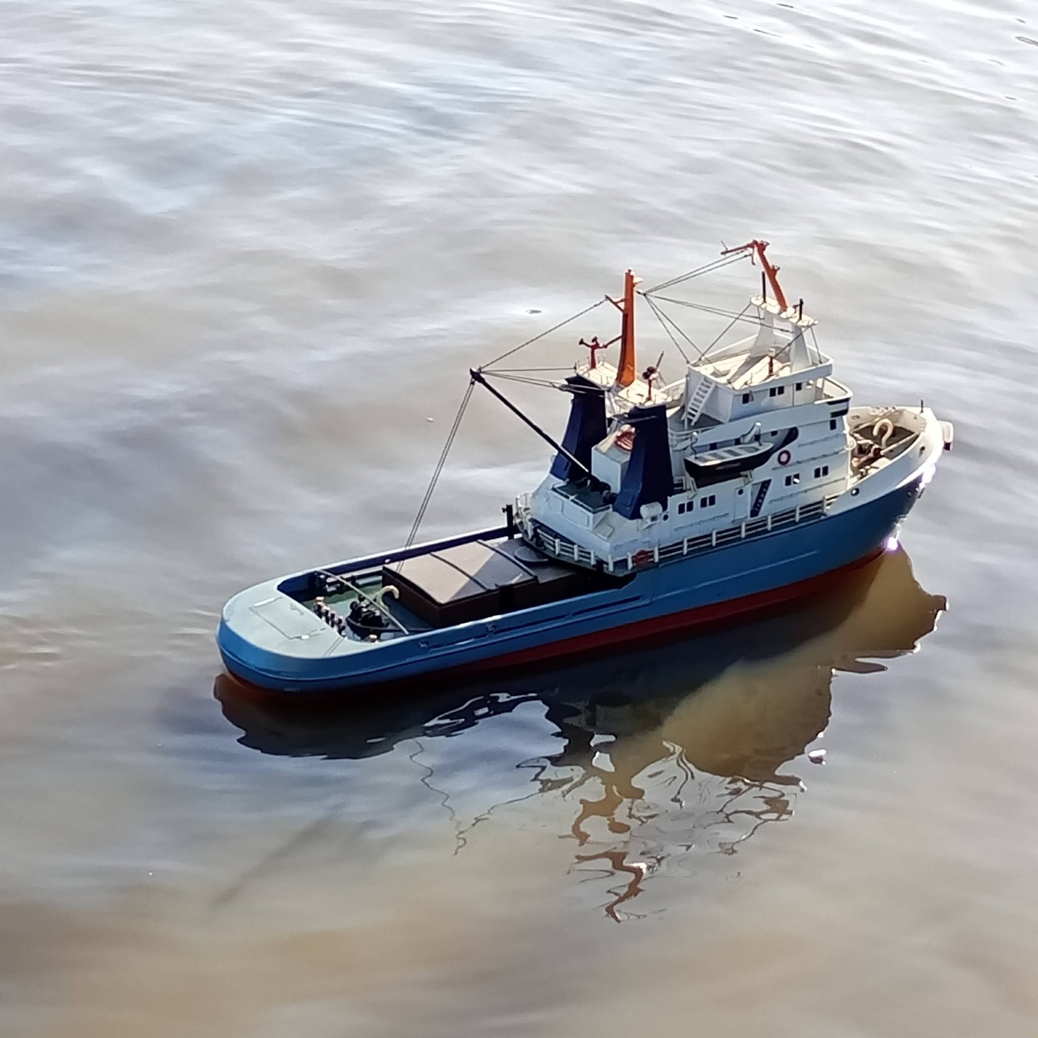 A model ship floating on water with visible ripples and reflections.
