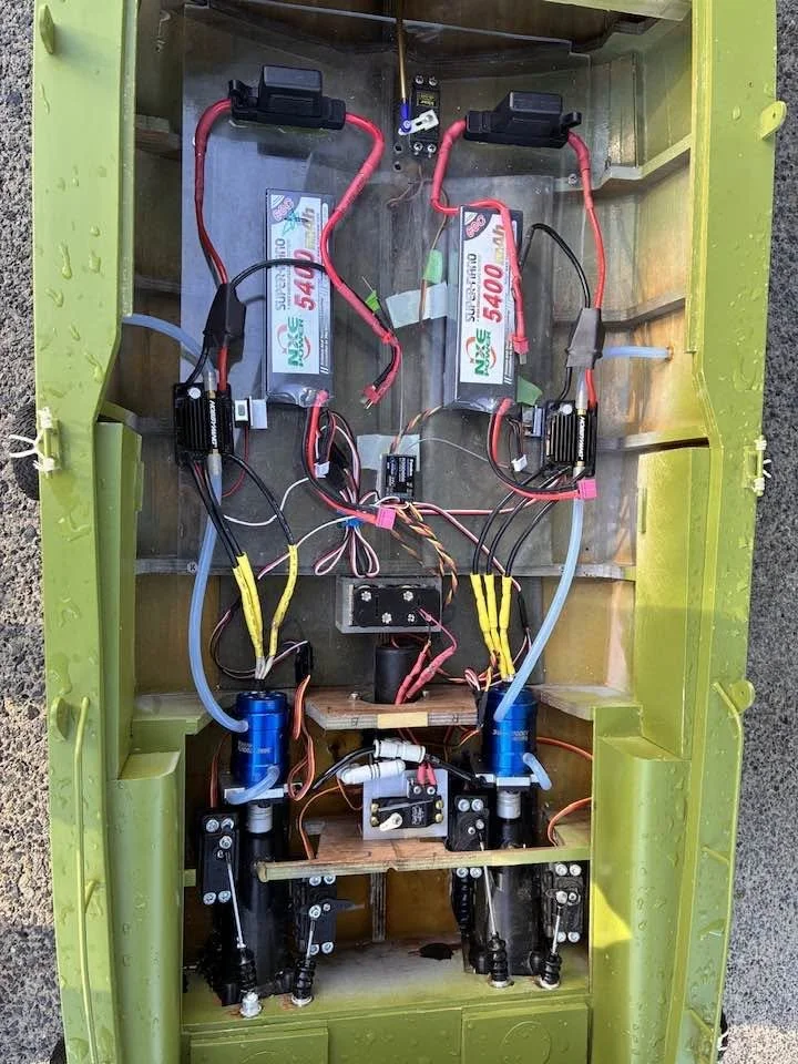 Inside view of a small electric vehicle or robot chassis with battery packs, wiring, and electronic components.
