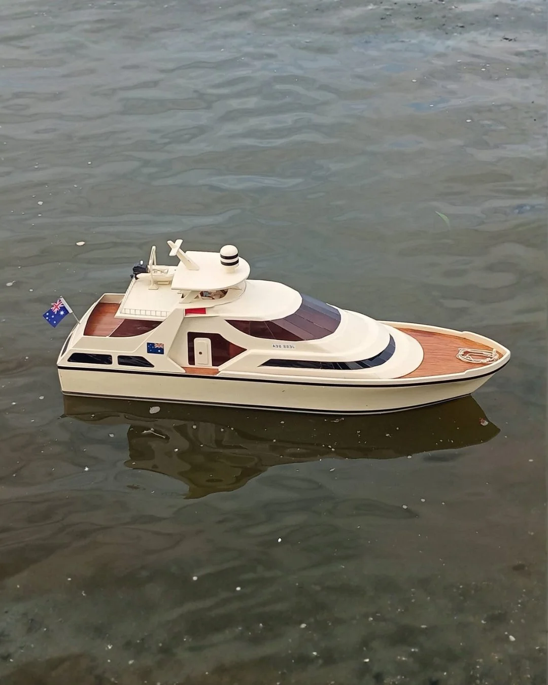 Model yacht boat floating in water with Australian flags