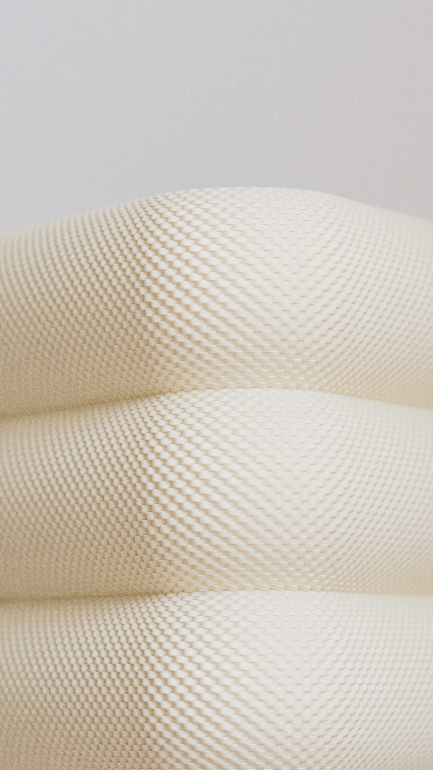 Close-up of three stacked textured white cushions with a triangular pattern.
