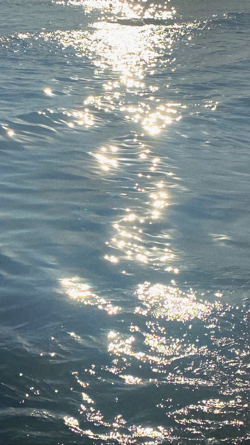 Sunlight reflecting off the surface of the ocean, creating sparkling highlights and a shimmering path across the water.