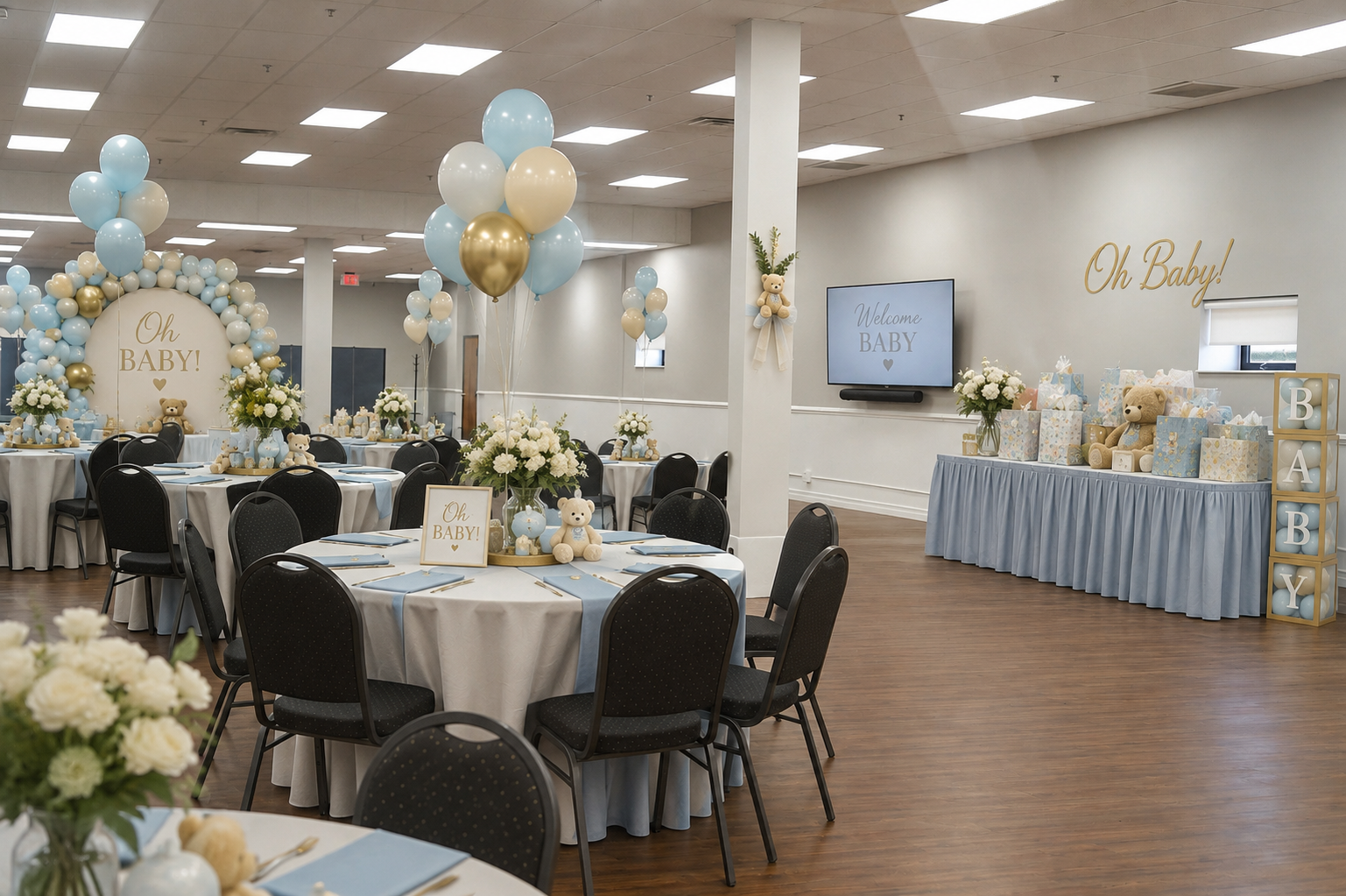 Decorated banquet hall for a baby shower with round tables, black chairs, balloon centerpieces in blue, gold, and white, floral arrangements, teddy bears, welcoming sign saying "Oh Baby!", gift table with presents, teddy bears, and "BABY" signs, and a TV screen displaying "Welcome BABY".