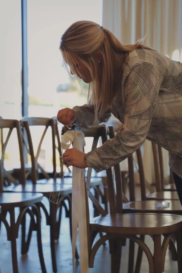 wedding planner puts bows on chairs  in charlotte north carolina