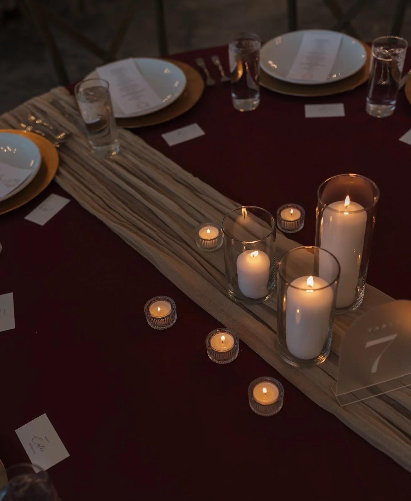 A table decorated with candles, plates, glasses, and cutlery for a formal event.