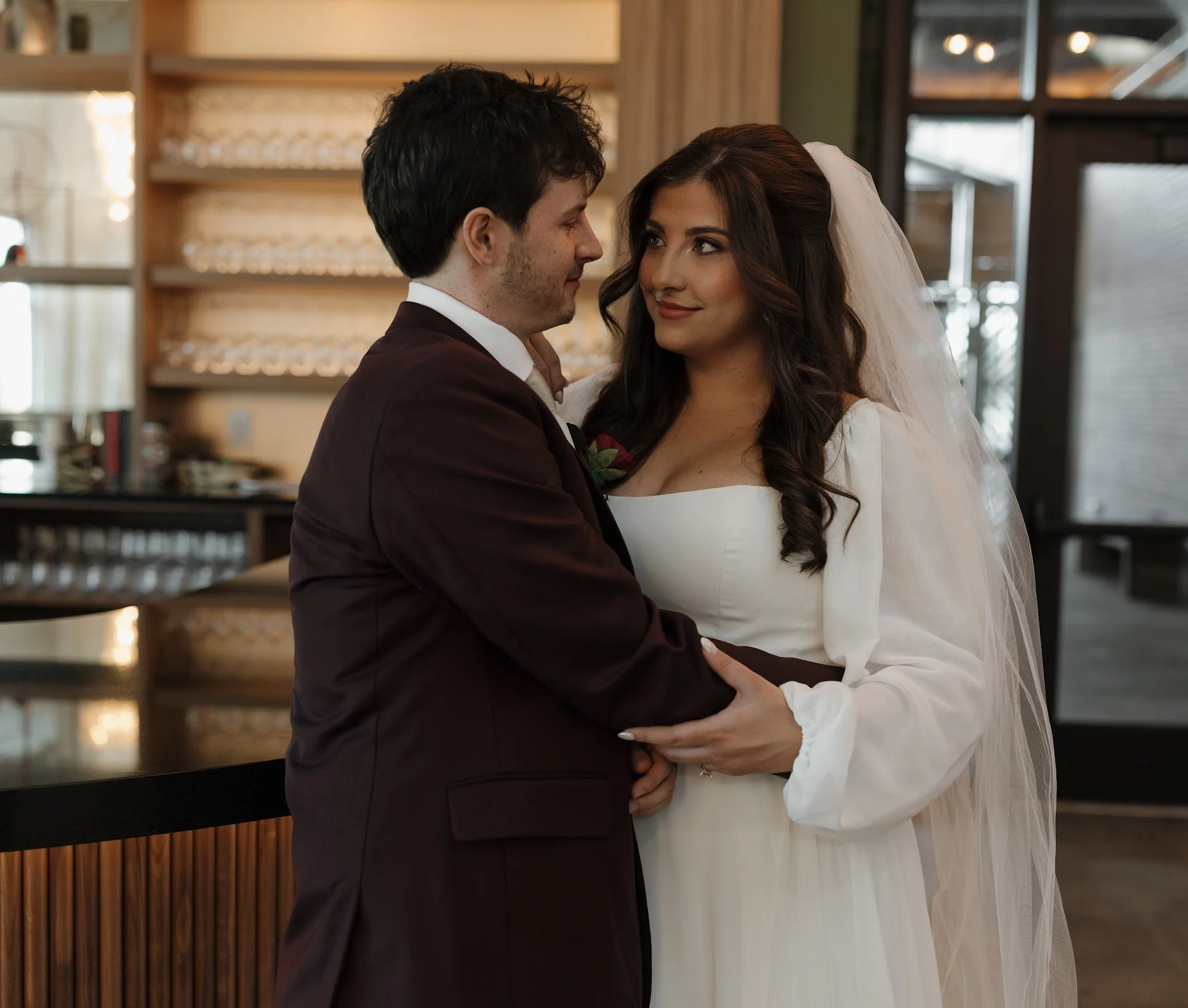 A newlywed couple embracing and gazing into each other's eyes indoors.