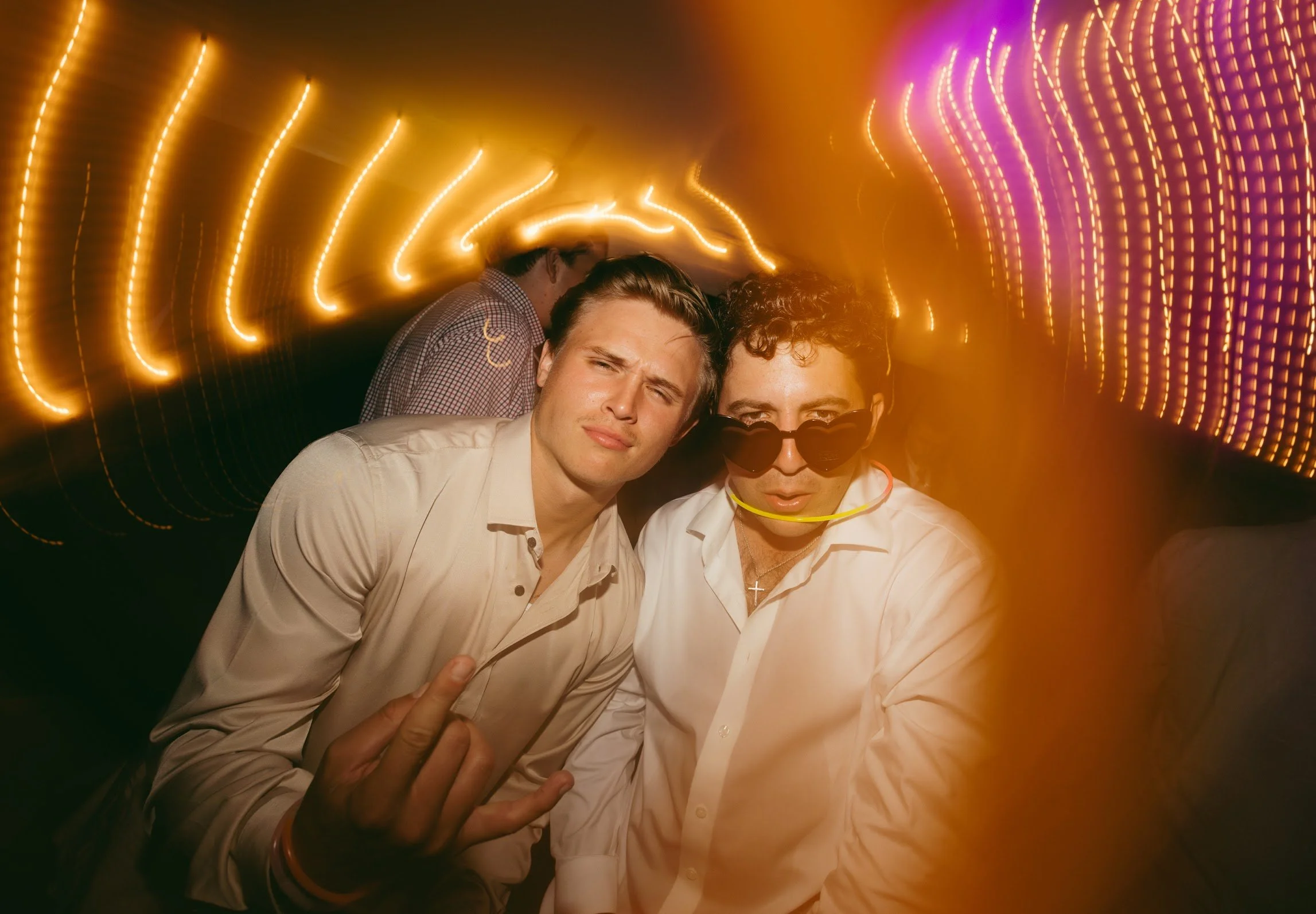 Two men having fun at a party with colorful lights and blurred motion effects in the background.