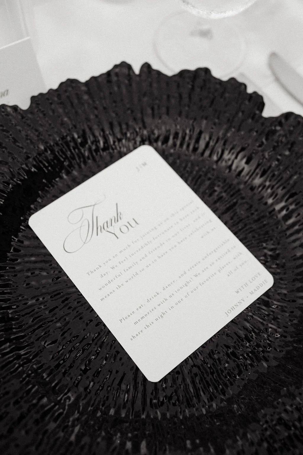 Thank you card placed inside a black, textured basket, with a message from Johnny Madue.