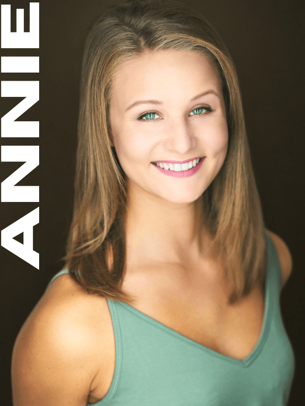 Portrait of a young woman with light brown hair, blue eyes, and a bright smile wearing a sleeveless green top.