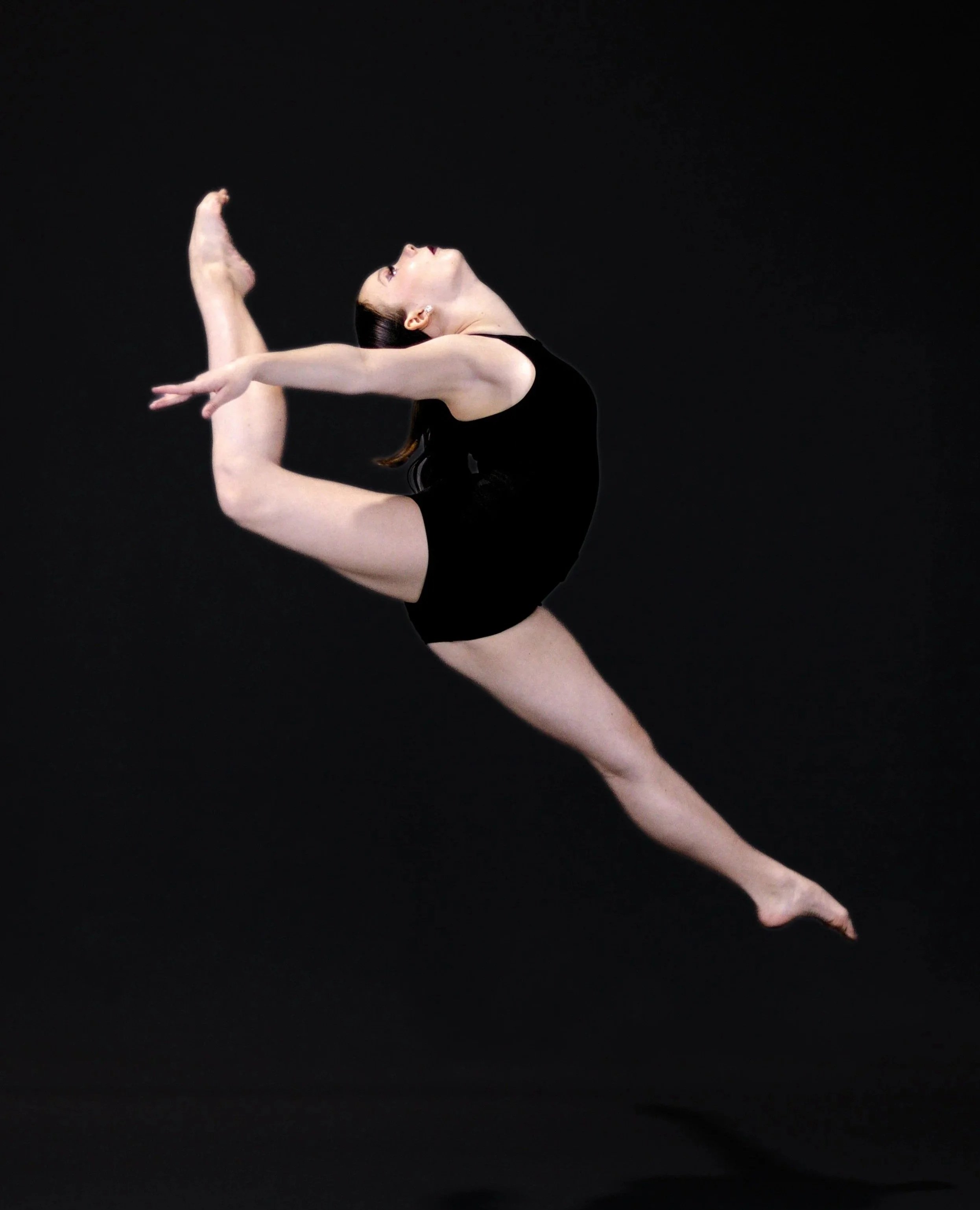 A female contour dancer performing a pose with one leg lifted high behind her and her arms extended forward on a black background.