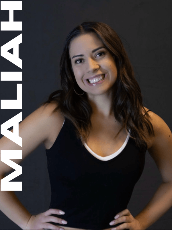 A woman with long dark hair, smiling, wearing a black sleeveless top with white trim, standing against a dark background. The name watermark 'MALAHY' is on the left side of the image.
