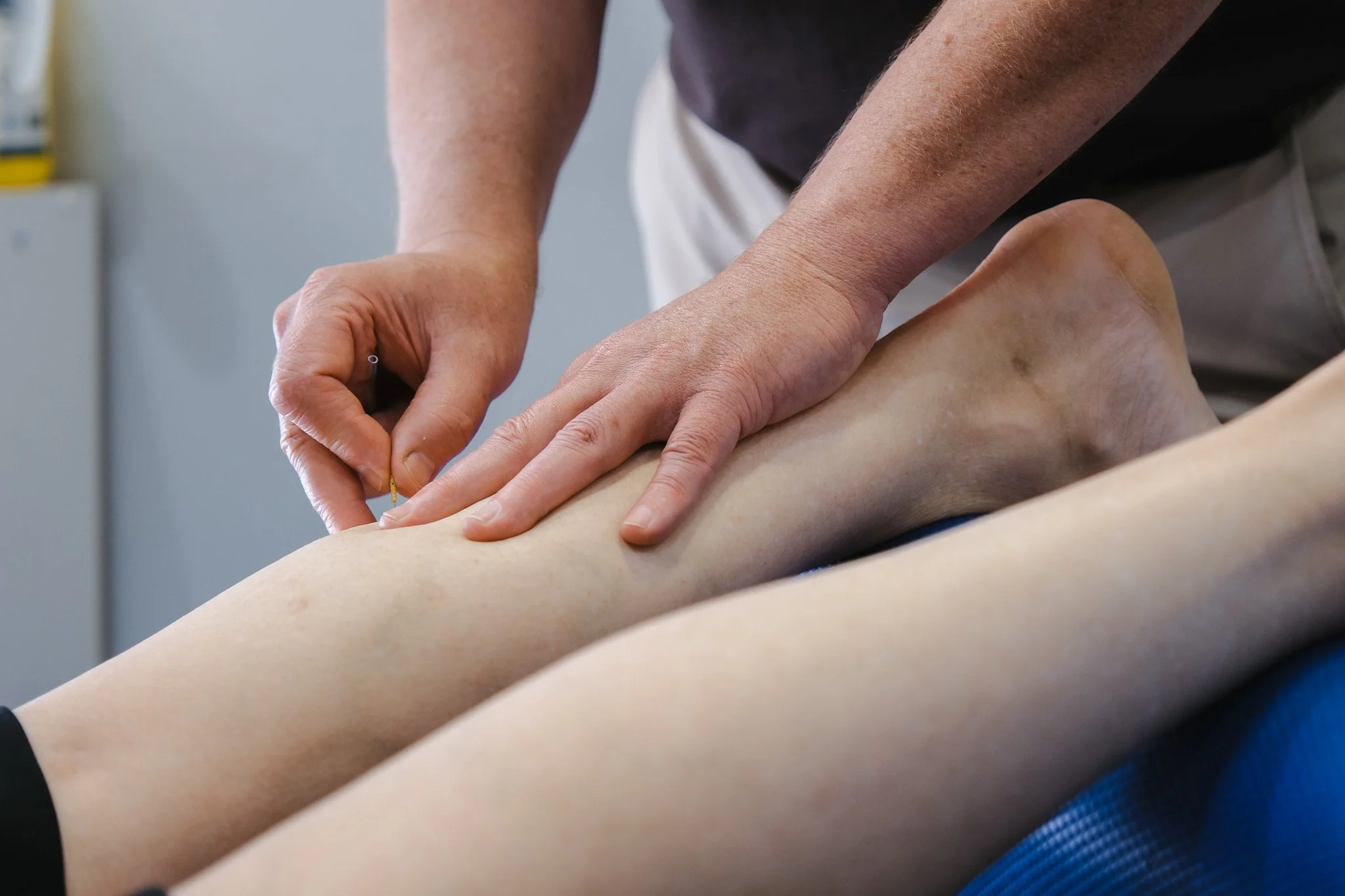 Bunbury Physio - A person providing chiropractic or medical care to another person's leg, with hands applying pressure and possibly performing a treatment or examination.
