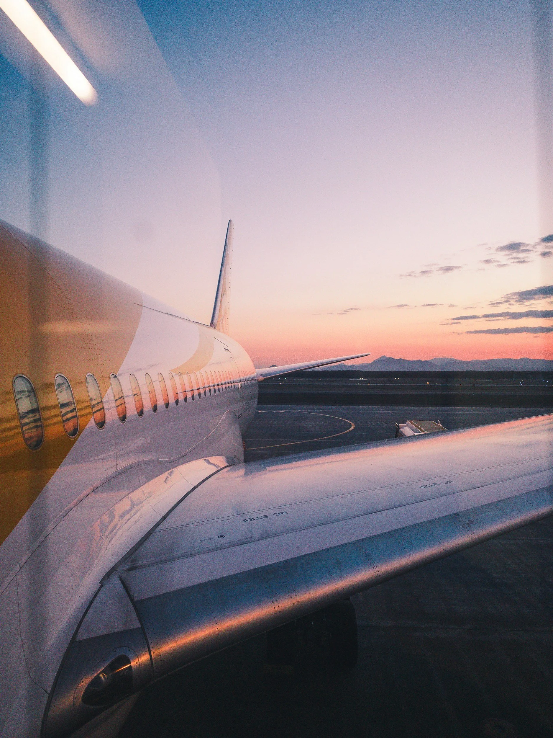 Bunbury Physio - View of an airplane wing and engine at sunset with hills in the distance, Busselton Airport.