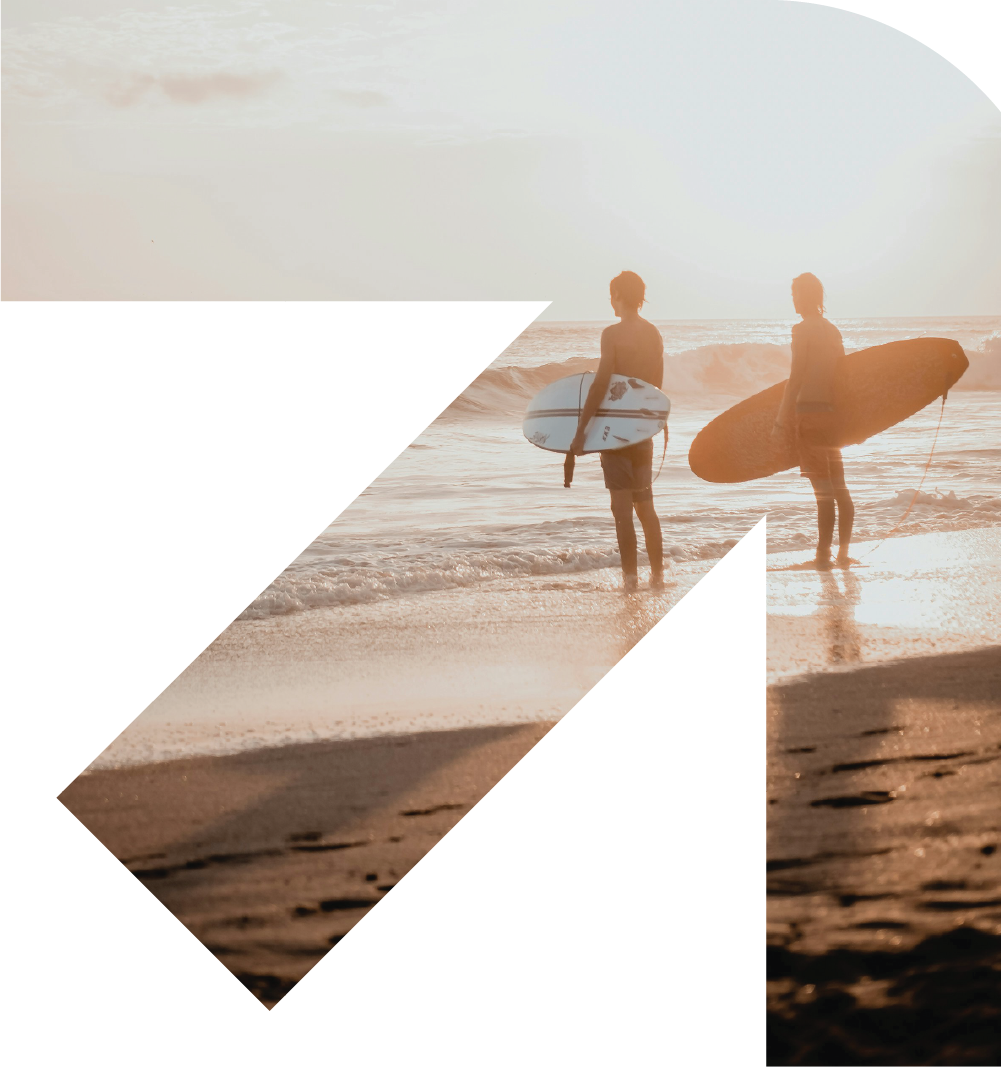 Bunbury Physio - Two surfers standing at the shore with surfboards, watching the sunset over the ocean.