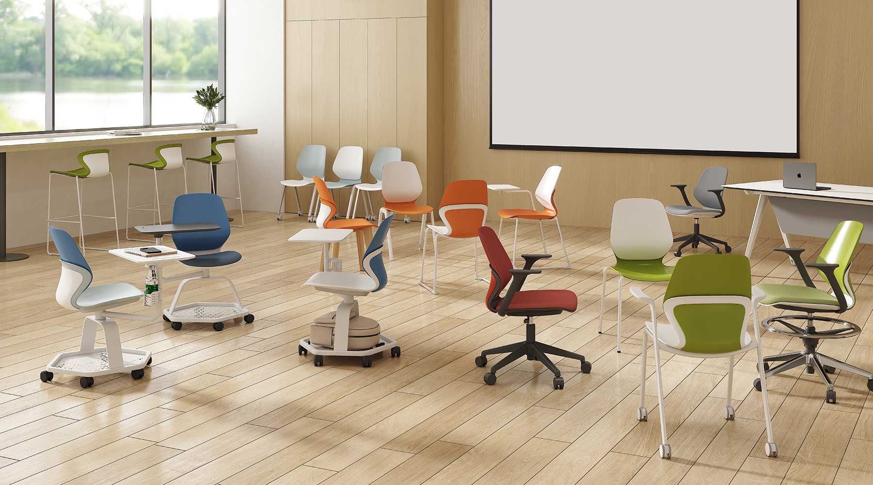 Modern conference room with colorful ergonomic chairs, a large screen, a desk with a laptop, and a large window overlooking greenery.