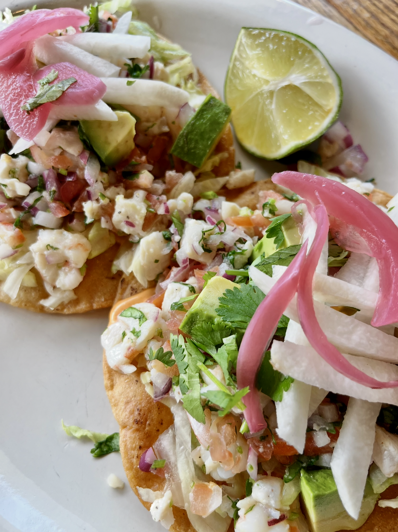 tostadas with seafood, pickled onions, and lime wedge