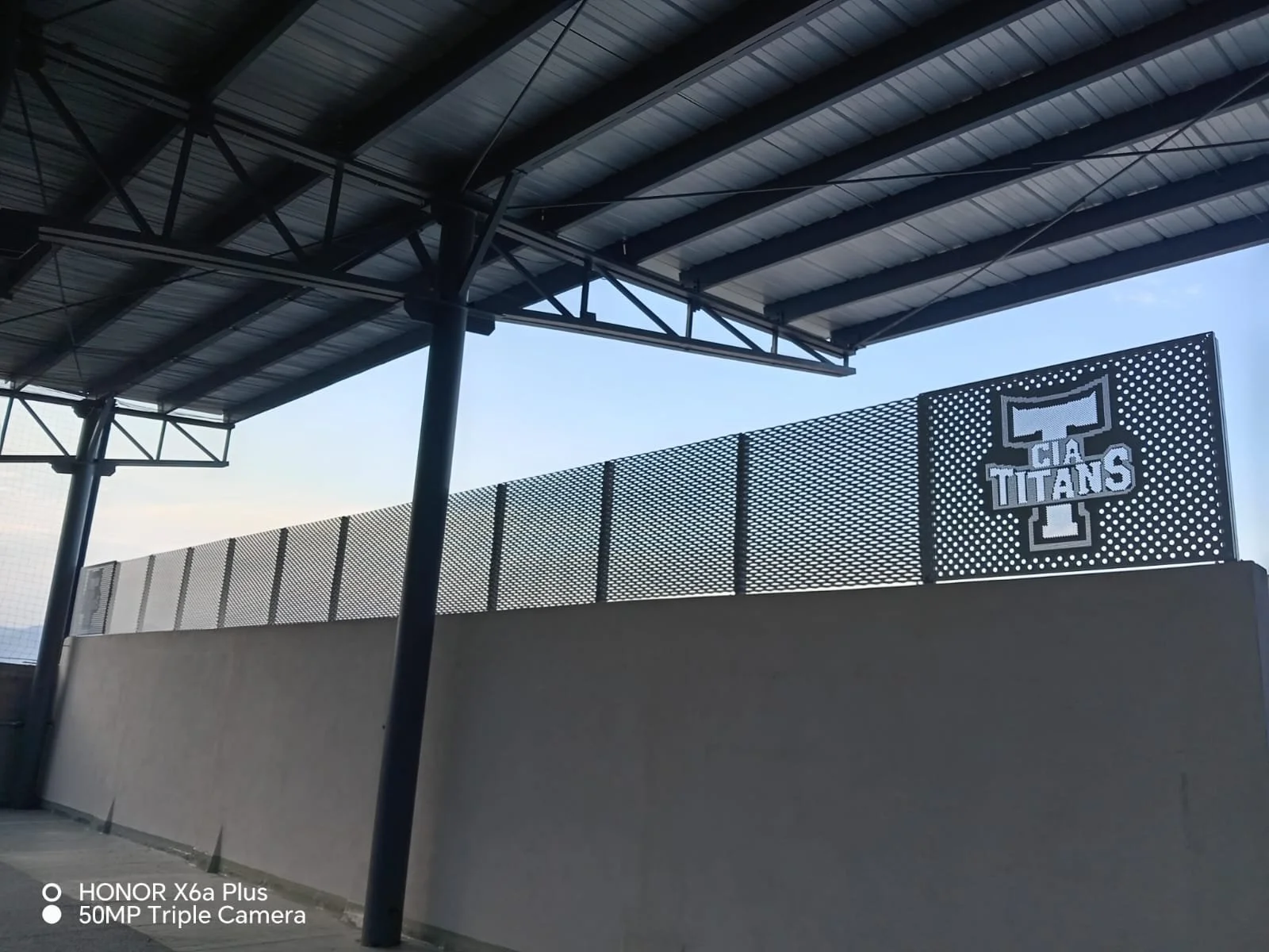 Estructura de un estadio con cartel que dice 'GIA TITANS' en letras grandes y un fondo de cielo azul.