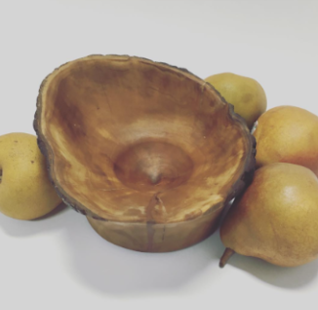 A cracked, hollowed-out coconut shell surrounded by four pears on a white background.