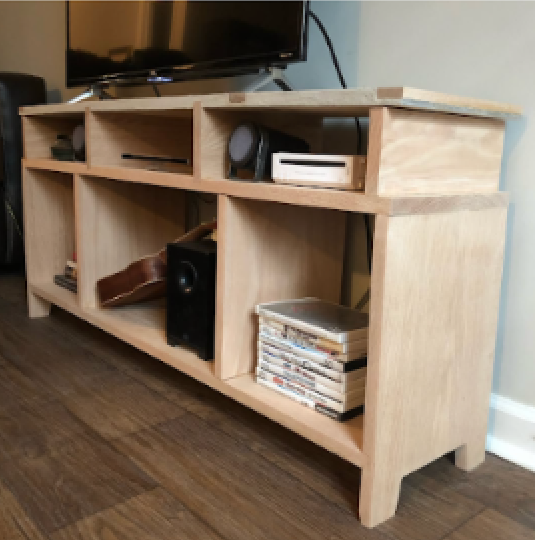 Wooden entertainment center with multiple compartments holding a TV, speakers, remote, and stacks of CDs or DVDs.