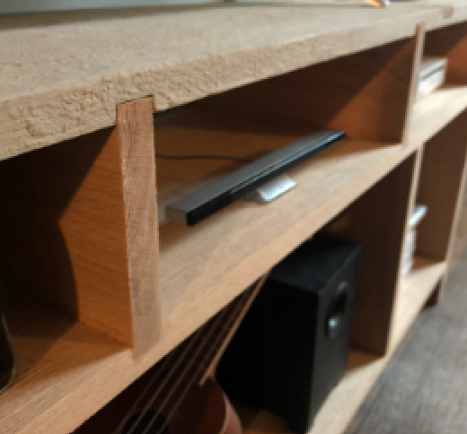 A wooden entertainment center with a flat-screen TV, a speaker underneath, and books in the compartments.