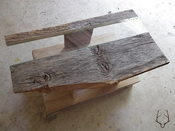 A wooden table with a glass top on a concrete floor.