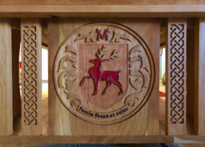 Wooden furniture piece with a carved emblem of a red deer and the phrase "Tennis from a dear" underneath.