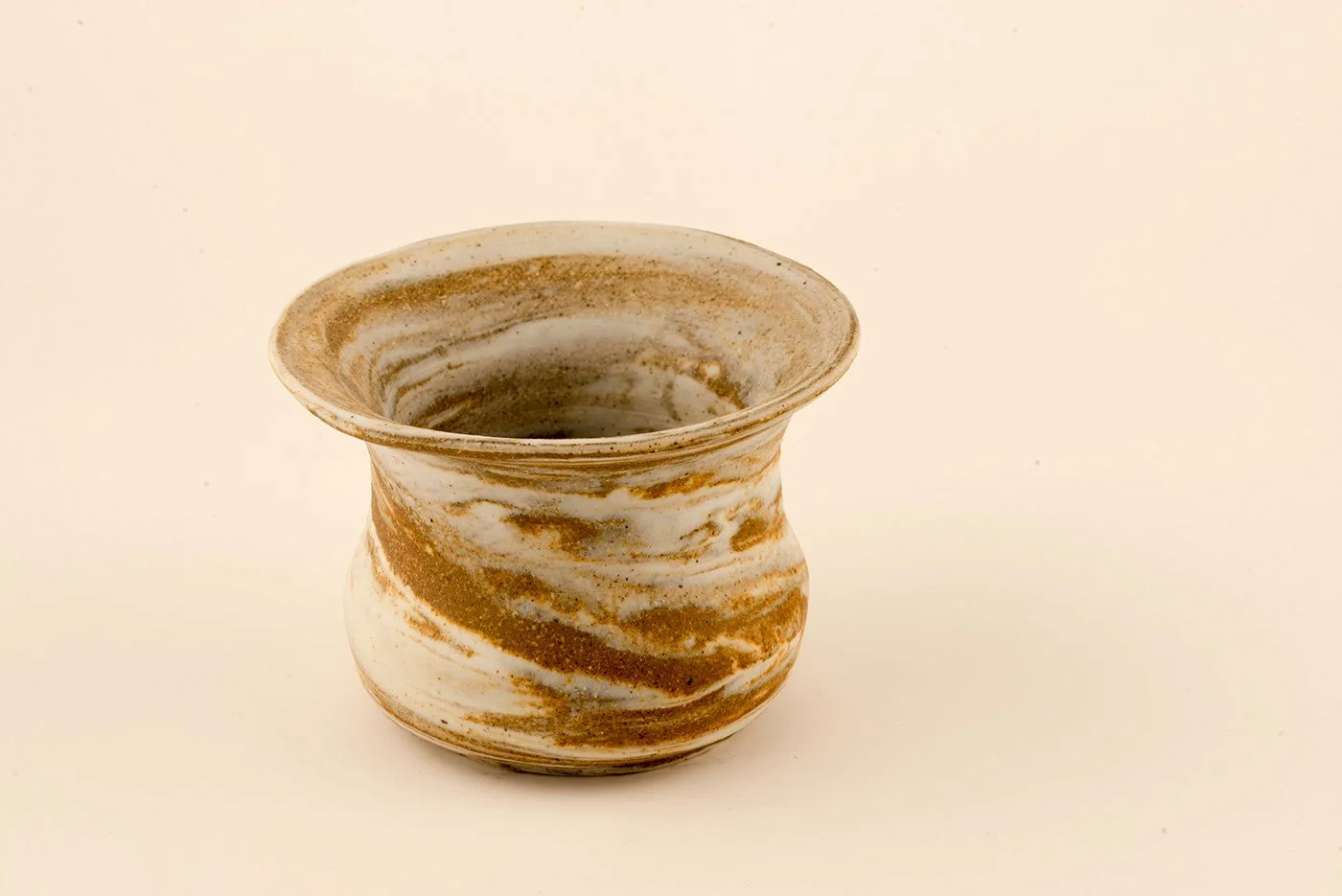 A ceramic vase with a marbled pattern of brown and white swirls, set against a plain light background.