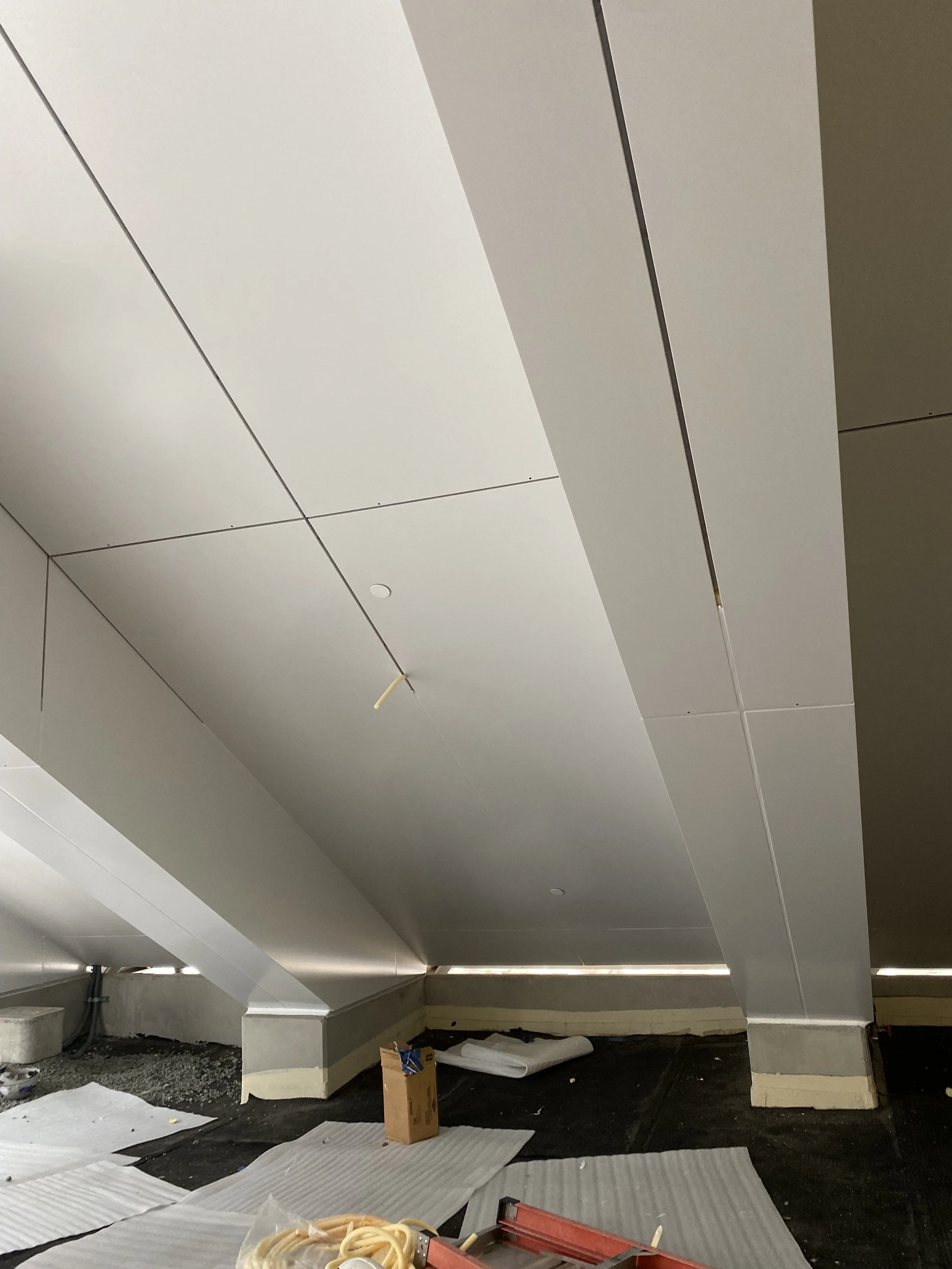 Construction site with unfinished ceiling, tools, and materials scattered on the floor.